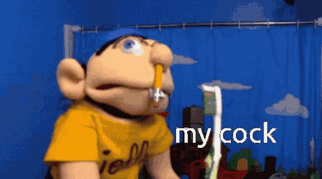 a puppet with a yellow shirt that says jelly on it is holding a toothbrush and saying my cock