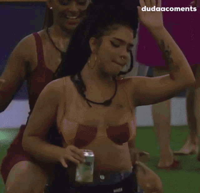 a woman in a bikini is sitting on the ground holding a can of soda .