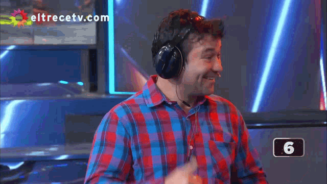 a man wearing headphones gives a thumbs up in front of a sign that says 6