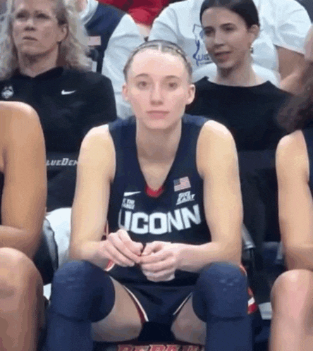 a female basketball player wearing an iconn jersey sits on the court