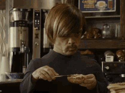 a man with a mustache is eating a piece of bread with butter .