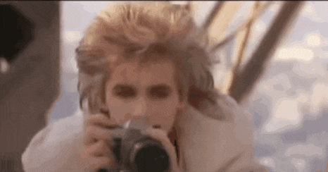 a man is taking a picture with a camera while wearing a white jacket .