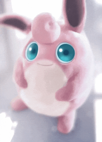 a pink stuffed animal with blue eyes is looking up
