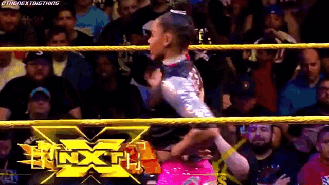 a woman is wrestling a man in a wrestling ring with a crowd watching .