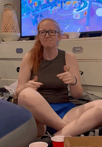 a woman sitting in front of a television with the words " i think i should be or feeling " on the screen