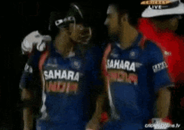 two men wearing sahara india jerseys are hugging each other