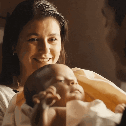 a woman holds a baby in her arms and smiles