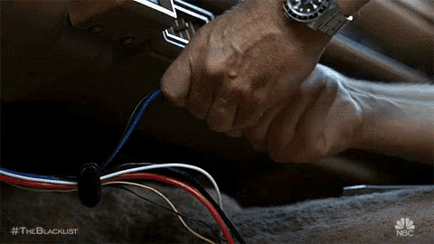 a close up of a man 's hands working on wires in a car