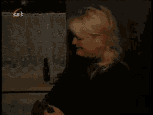 a woman in a dark room with a sbs logo above her