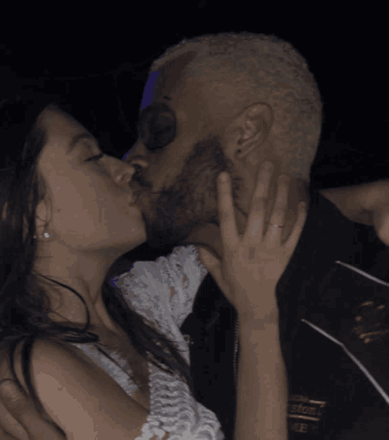 a man and a woman are kissing and the man is wearing a jacket that says boston on it
