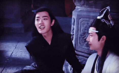 two young men are sitting next to each other on the floor and talking .