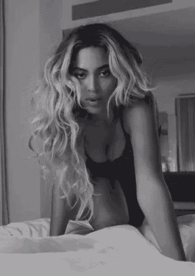a woman in lingerie is kneeling on a bed .