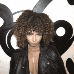 a woman with curly hair wearing a leather jacket