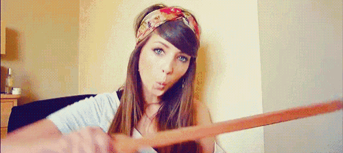 a woman wearing a floral headband is blowing a kiss while holding a wooden stick