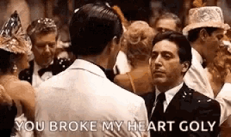 a man in a suit and tie is talking to another man in a crowd at a party .