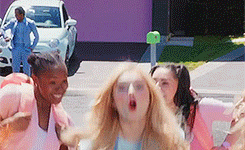 a group of girls are standing in front of a purple house .