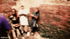 a blurry picture of people standing in front of a brick wall .