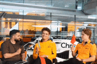 three men are sitting in front of a car that says cadence on it