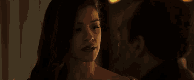 a man and a woman are kissing in a dark room . the woman is wearing red lipstick .