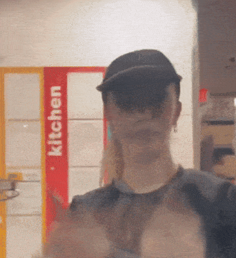 a woman in a black hat stands in front of a kitchen sign