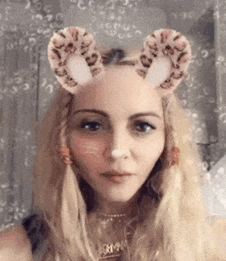 a close up of a woman wearing a cat mask with ears on her head .