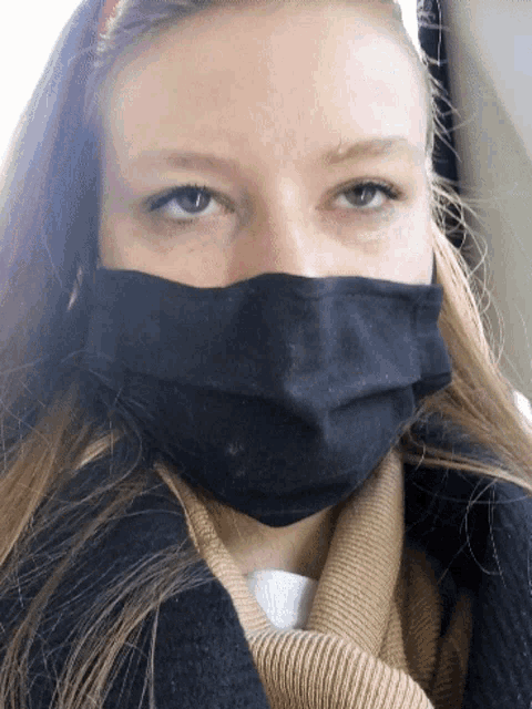 a woman wearing a black face mask and a scarf around her neck