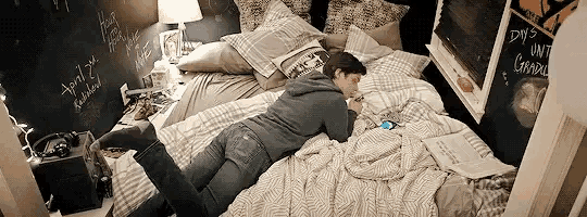 a person is laying on a bed looking at their phone .