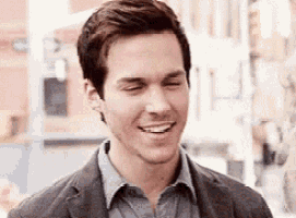 a man in a suit and tie is smiling with his eyes closed and his mouth open .
