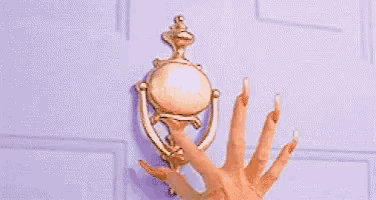 a woman 's hand with long nails is holding a door knocker on a door .