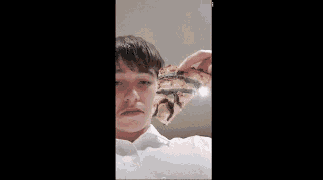 a young man is holding a slice of pizza over his face