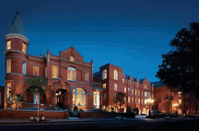 a large red brick building with a tower on top of it is lit up at night