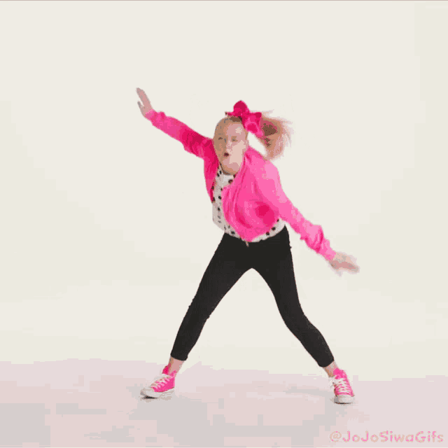 a girl with a pink jacket and black pants is dancing