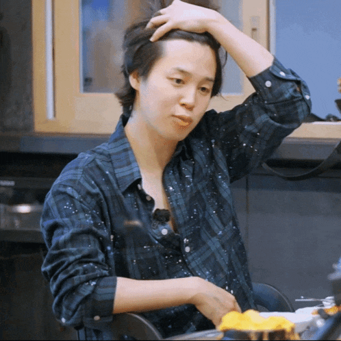 a man in a blue plaid shirt is sitting at a table