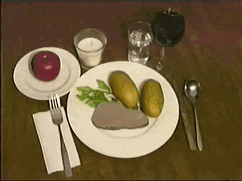 a plate of food with meat potatoes and an apple on a wooden table