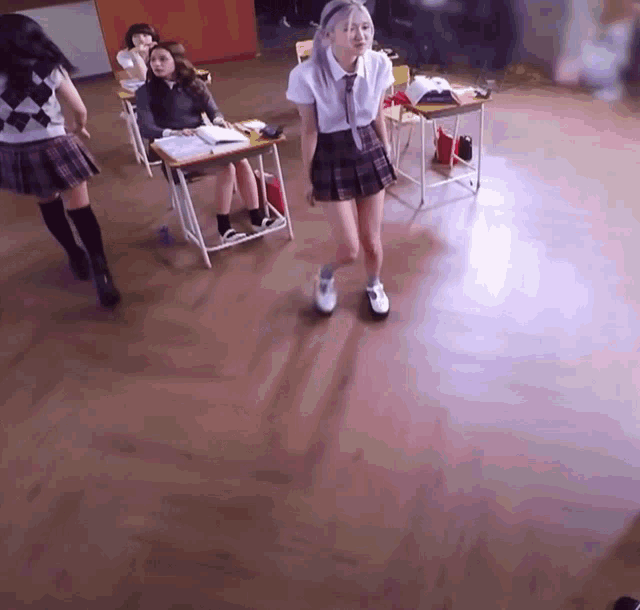 a girl in a plaid skirt is standing in a classroom with other girls