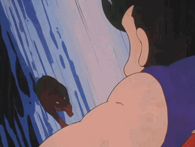 a man in a purple shirt is looking at a snake on a wall
