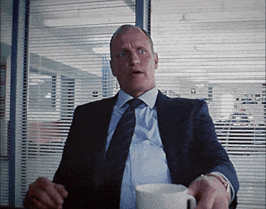a man in a suit and tie is holding a white cup