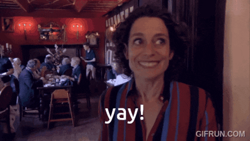 a woman in a restaurant says yay in front of a group of people