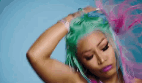 a woman with green hair and pink lipstick is holding her hair .
