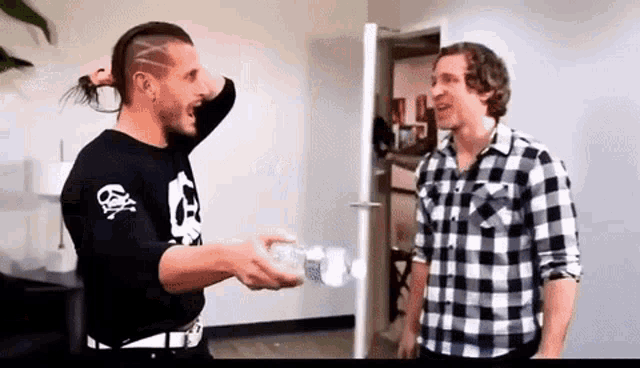 two men are standing next to each other in a room and one of them is wearing a black shirt with skulls on it