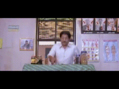 a man is sitting at a table in a room with posters on the walls