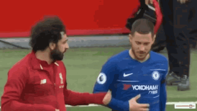 a soccer player in a blue yokohama jersey is touching the chest of another player