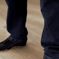 a person standing on a wooden floor wearing blue jeans