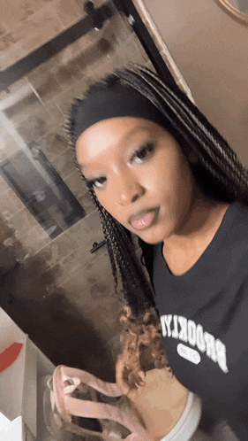 a woman wearing a black shirt that says brooklyn looks at herself in the mirror