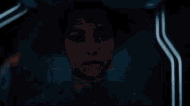 a young girl is sitting in a dark room looking at something .