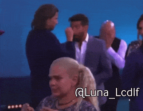 a group of people are standing in front of a blue background and the woman is crying