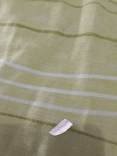 a green and white striped fabric with a small piece of paper laying on it