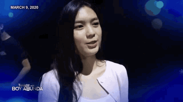 a woman is standing in front of a blue background that says tonight with boy abunda on it .