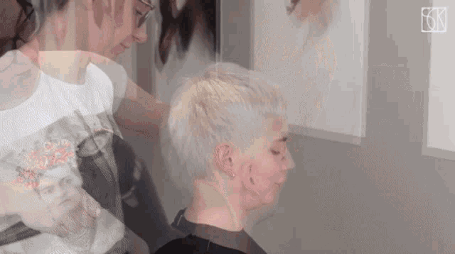 a woman is getting her hair cut by a hairdresser while wearing a shirt with a picture of a woman on it