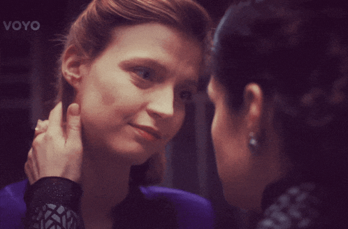 a woman touches another woman 's face with the words voyo visible in the corner
